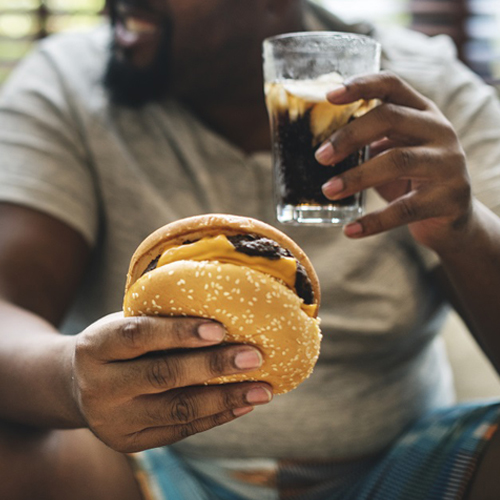 man holding hamburger and glass of soda